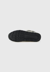 Semelle en caoutchouc noir d'une sneaker avec des semelles à motifs et "Armani Exchange" embossé sur la partie médiane de la semelle.