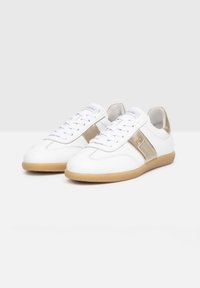 Baskets en cuir blanc avec une bande d'accent dorée, semelle en caoutchouc plate marron, et lacets blancs. Conception à bout rond avec support de cheville rembourré.