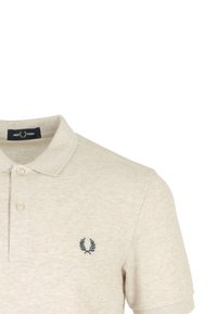 Beige poloshirt van textuurstof, met een placket met twee knopen en een donker geborduurd logo op de linkerkant van de borst.