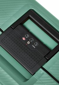 Valigia turchese con superficie in plastica texturizzata, dotata di un meccanismo di chiusura nero con due chiavi tonde, tre dischi e un pannello perforato.