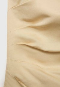 Tissu beige à texture froncée, présentant une finition douce, lisse et mate. Le design comprend des plis horizontaux formant un motif ondulé.