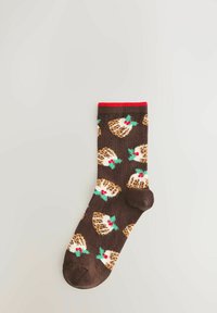 Brown sock with red top band, decorated with repeated Christmas pudding designs featuring white icing, green holly leaves, and red berries.