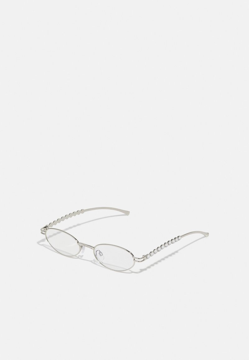 Óculos ovais com uma armação metálica prateada, lentes transparentes e detalhes texturizados em contas nas hastes. Design leve com braços curvos.