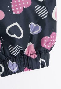 Tissu marine avec divers cœurs à motifs en rose, violet et blanc ; possède un poignet élastiqué pour un ajustement confortable.