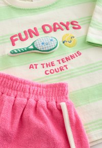 Green striped T-shirt with pink "FUN DAYS AT THE TENNIS COURT" text, tennis racquet and smiling tennis ball embroidery; pink terrycloth shorts.