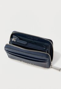 Cartera de cuero azul marino con exterior texturizado, cremallera plateada y múltiples compartimentos, incluyendo un espacio para tarjetas y un bolsillo con cremallera para monedas.