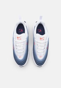 White sneakers with blue gradient design, textured pattern on upper, features red accents, laces, and 'AIR' branding on tongue and sides.