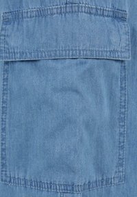 Denim tkanina u svijetloplavoj boji s glatkom teksturom. Ima veliki, kvadratni džep sa pojačanim šavovima na vrhu.