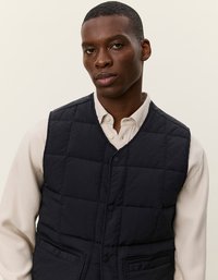 Ναυτικό στρώμα από τηγανισμένο ύφασμα με σχέδιο μπροστινών κουμπιών, διαθέτει δύο μπροστινές τσέπες και μαλακή υφή, καλυμμένο από ένα ανοιχτόχρωμο πουκάμισο.