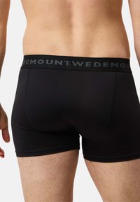 Czarne bokserki męskie wykonane z elastycznego materiału o jednolitym wzorze. Posiadają płaski pas z logo "MOUNT", bezszwowe wykończenie oraz dopasowany krój.