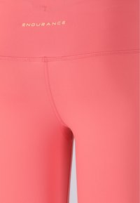 Leggings sportivi rosa con una texture liscia, dotati di una alta vita e di un logo sottile "ENDURANCE" in oro sul retro.