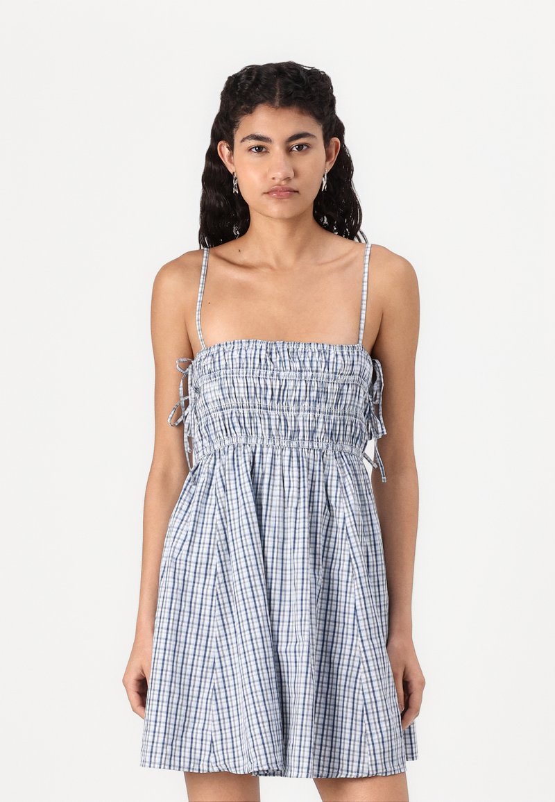 Rochie cu bretele spaghetti în carouri alb-albastre, cu un bodice smocat, elastic și fustă fluidă. Material din bumbac crocant, textură ușoară.