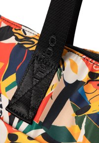 Kleurvolle stoffen tas met een abstract patroon met rode, gele en blauwe accenten; zwarte nylon schouderbanden met een gestructureerd oppervlak en logo.