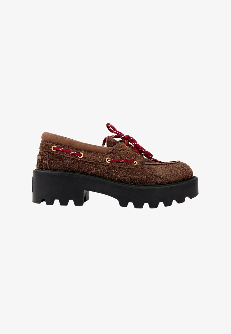 Mocassin marron texturé avec une semelle épaisse noire à crampons et des lacets rouges passant par des œillets dorés sur le côté et à l'avant.