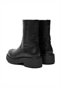 Czarne skórzane botki za kostkę o teksturowanym wykończeniu, z elastycznymi panelami bocznymi i masywną gumową podeszwą. Posiadają logo na pięcie.