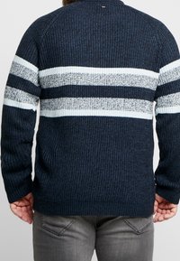 Maglione lavorato a maglia blu navy con strisce orizzontali bianche e grigio chiaro, caratterizzato da una texture a costine e un design con colletto a girocollo.