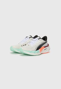 Weiße Sportschuhe mit schwarzen Akzenten, strukturiertem Obermaterial, weißen Schnürsenkeln und einer bunten Sohle in Mintgrün, Orange und Schwarz.