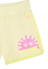 Pantaloni shorts gialli con una vita a coste, dettagli in giallo neon e una grafica a forma di sole in paillettes rosa con cuori e il testo "BILLIEBLUSH".