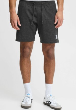 Shorts de sport gris foncé en matériau doux, dotés d'une taille élastique avec cordon de serrage et d'une petite étiquette de logo sur le côté.