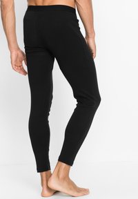 Schwarze Leggings aus elastischem Material, mit figurbetontem Schnitt, knöchellangem Design und einem elastischen Bund ohne sichtbare Nähte.