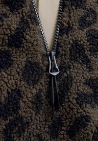 Bruine en zwarte fleece zip-up top met een gestructureerd oppervlak, een zwarte rits met een trekkoord en een hoge kraag.