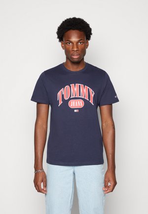 Marineblå bomulls t-skjorte med stort rødt og hvitt "TOMMY JEANS" logo over brystet, korte ermer og klassisk rund hals.