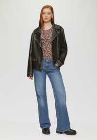 Zwarte leren motorjack, top met bloemenpatroon, blauwe flared jeans en zwarte stoere laarzen. Eenvoudig ontwerp met contrasterende texturen.