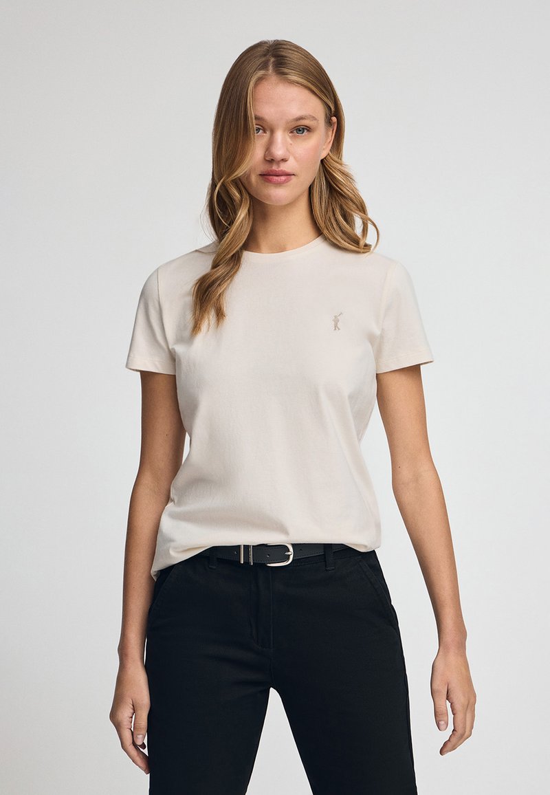 Crème, aansluitend T-shirt van zachte katoen met korte mouwen en een ronde hals. Bevat een subtiel geborduurd logo op de borst.
