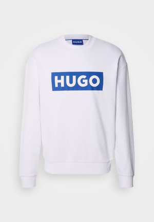 Biela mikina s dlhými rukávmi, s veľkým modrým obdĺžnikovým logom "HUGO" napísaným bielymi veľkými písmenami cez hrudník.