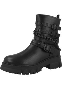 Bota de tobillo de cuero negro con suela gruesa, que presenta múltiples correas, tachuelas metálicas y un detalle de cadena para mayor estilo.