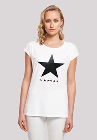White cotton t-shirt with rolled sleeves, featuring a large black star graphic and smaller stars below. Simple, casual design.