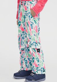 Pantalones de invierno coloridos en una base blanca con patrones abstractos en rosa, verde y azul. Presenta un parche con logo y bolsillos laterales.