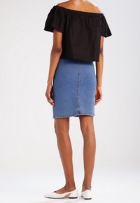 Crop top nero senza spalline e gonna fitted in denim blu. Scarpe bianche flat. Tessuto liscio, design semplice, senza stampe.