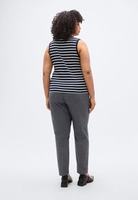 Μπλε ναυτικό και λευκό ριγέ αμάνικο τοπ με στρογγυλεμένο λαιμό, συνδυασμένο με γκρι υφασμάτινο παντελόνι και μαύρα κλειστά παπούτσια. Πλάγια όψη από πίσω.