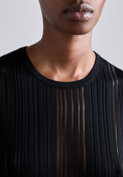 Svart topp med vertikal ribbet tekstur, rund hals, og semi-transparente seksjoner som fremhever et lagdelt design og glatt stoff.