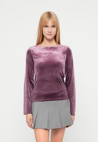 Langermet topp i myk, elastisk fløyel med båthals og en rik lilla farge, kombinert med et plisset skjørt i grått.
