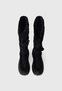 Cizme negre de iarnă cu manșete înalte din blană pufoasă și partea superioară texturată neagră. Au șireturi înnodate și o talpă robustă din cauciuc.