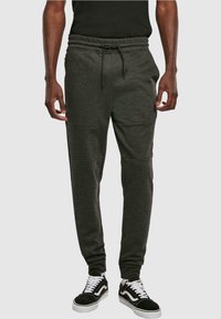 Donkergrijze sweatpants met een trekkoord in de taille, taps toelopende benen en details in de zijkanten, gecombineerd met zwart-witte sneakers.