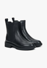 Černé kožené chelsea boots s elastickými bočními panely, zaoblenými špičkami, plochými gumovými podrážkami a poutky na patách pro snadné obutí.