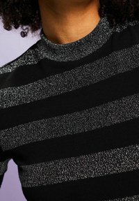 Czarny dzianinowy top z poziomymi, metalicznymi srebrnymi paskami. Dopasowany, z wysokim dekoltem i teksturowanym wykończeniem.