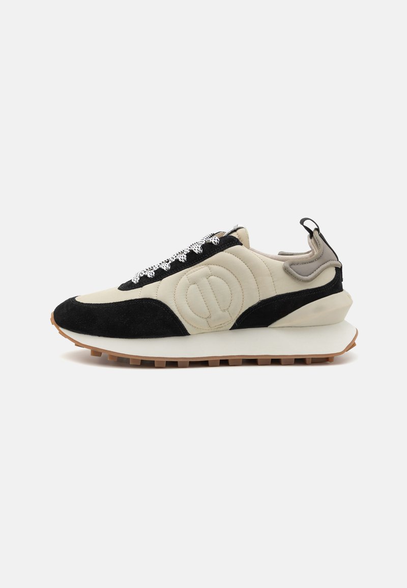 Zapatos deportivos con superior de cuero crema, detalles en ante negro, cordones blancos, entresuela texturizada y suela de goma marrón con tracción.
