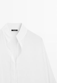 Hvid skjorte med krave og skjult knaplukning, lange ærmer og et Massimo Dutti-mærke inde i kraven.