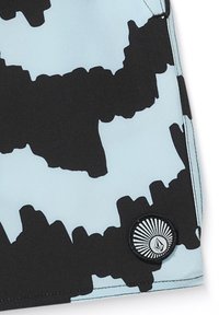 Costume da bagno a patter nero e blu chiaro con una texture morbida. Presenta un distintivo circolare nero con un design a raggi di sole e il logo.