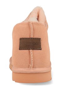 Perzikkleurige suède enkelboot met een zachte binnenvoering, gestikte details en een bruine label met "warmbat Australia" op de achterkant.