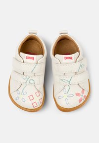 Weiße Lederschuhe mit zwei Klettverschlüssen, die bunte Blumen- und geometrische Stickereien sowie eine hellbraune Gummisohle aufweisen.