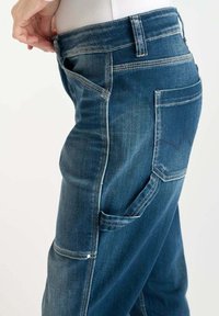 Pantalons cargo en denim avec un lavage bleu foncé, plusieurs poches et des coutures contrastées. Conçus avec une coupe décontractée et un tissu durable.