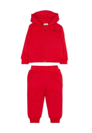 Completo per bambini rosso in due pezzi con giacca con cappuccio e zip e pantaloni con vita elastica, entrambi con polsini a costine.