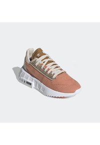 Pink and tan athletic sneaker with a textured upper, white sole, and flat laces. Features an Adidas logo and patterned canvas accents.