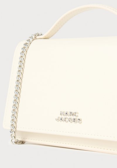 Kremfarvet taske i imiteret læder med sølvkæde som strop, der har en magnetisk klaplukning og det præget "Marc Jacobs" logo foran.