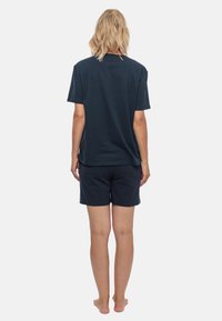 T-shirt in cotone blu navy con maniche corte e pantaloni corti abbinati, visti da dietro. Design semplice, vestibilità comoda e colori solidi.